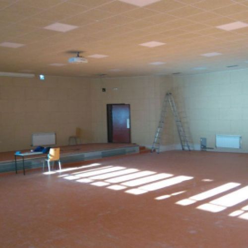 Imagen de sala grande con techo en obras con placas cuadradas